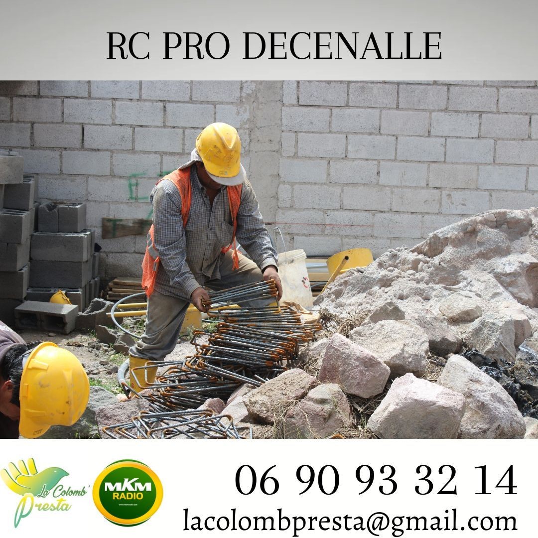 Construction worker in a yellow hard hat handling metal rebar near a pile of rocks.